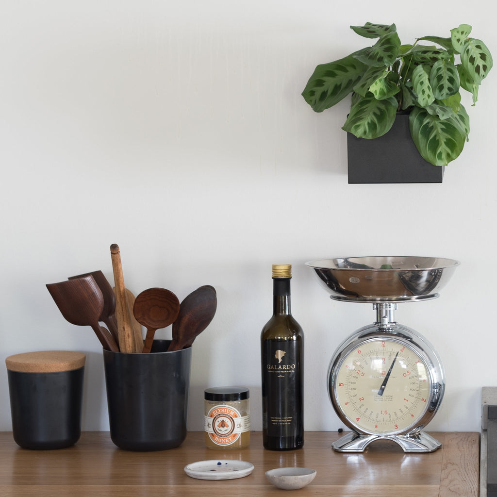 A lifestyle image featuring kitchen goods and a black powder-coated planter box.