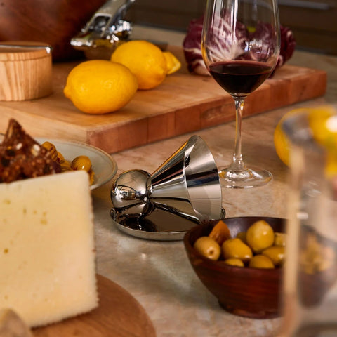 A variety of high-end kitchenware including a citrus press, wine glass, and cutting boards. 