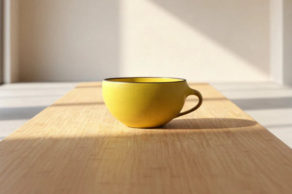 Yellow mug on a wooden table with sunlight casting shadows