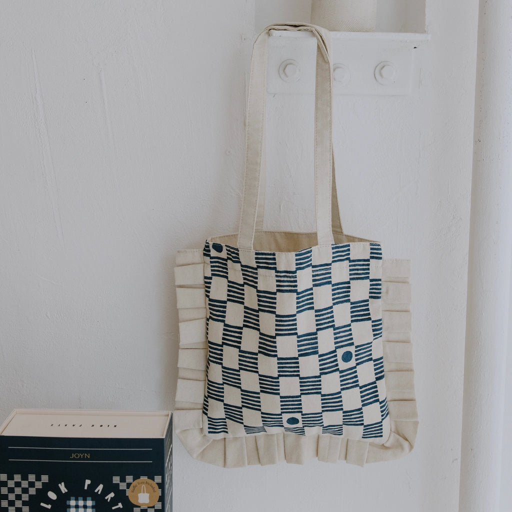 Tote bag with checkered pattern hanging on a white wall