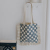 Tote bag with checkered pattern hanging on a white wall