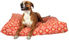 Dog sitting on a red patterned dog bed with a white background