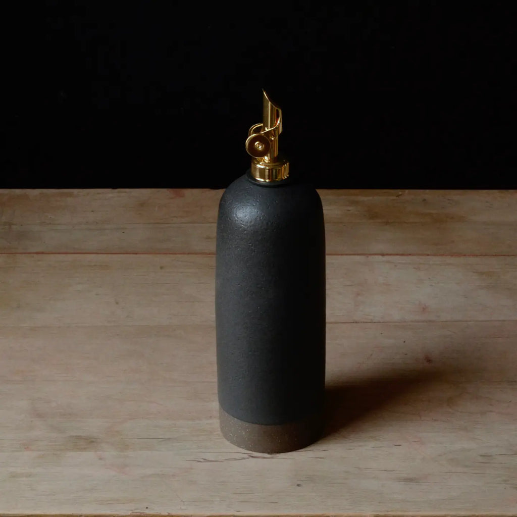 Black ceramic oil bottle with gold cap on a wooden surface