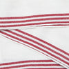 White woven fabric with red and white striped borders, shown folded to highlight the textile texture and stripe pattern.