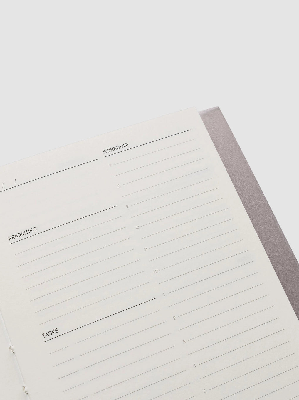 Close-up of a planner with sections for schedule, priorities, and tasks on a white background.