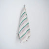 Striped towel with tassels hanging on a hook against a white background