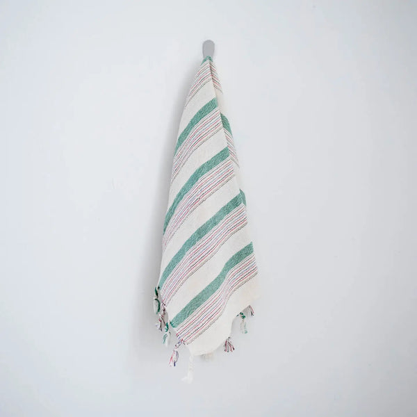 Striped towel with tassels hanging on a hook against a white background