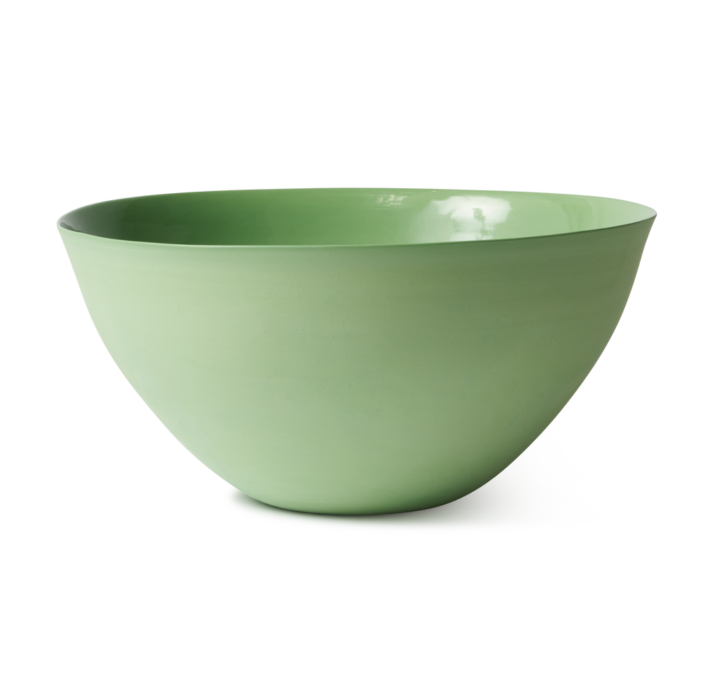 A matte sage green ceramic bowl with a wide, shallow depth, shown from a three-quarters perspective on a clean white background.