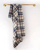 Plaid towel hanging on a gold towel rack against a white background