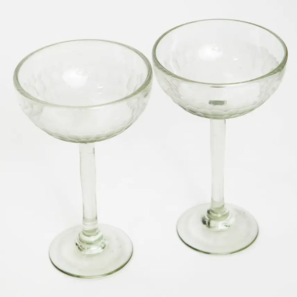 Two clear glass coupe glasses on a white background