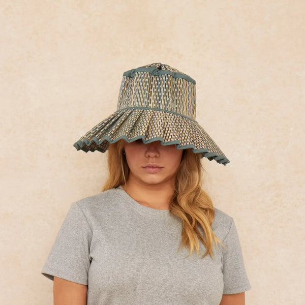 Person wearing a patterned sun hat against a beige background