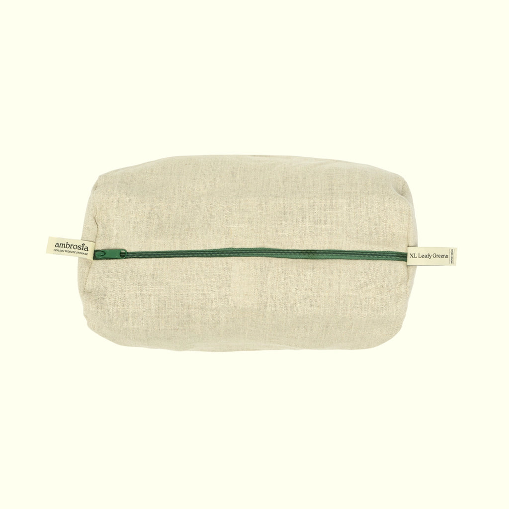 A rectangular beige linen pouch with a dark green zipper, featuring a small fabric brand tab on each end that reads 'ambrosia', set against a solid off-white background.