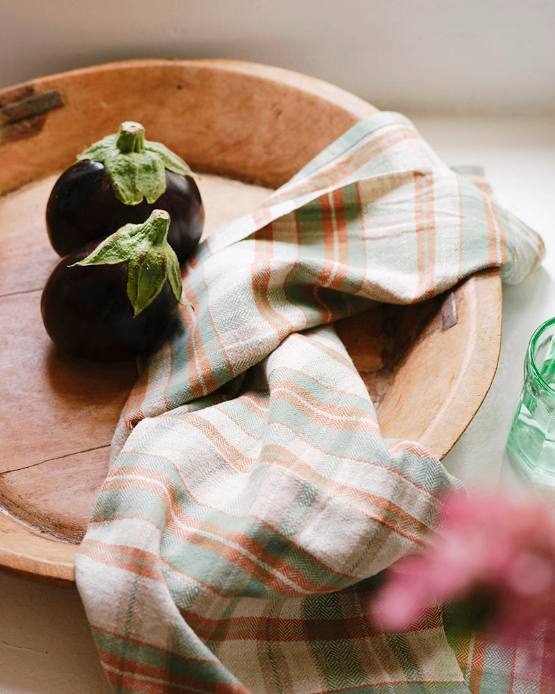 Two eggplants on a wooden plate with a checkered cloth