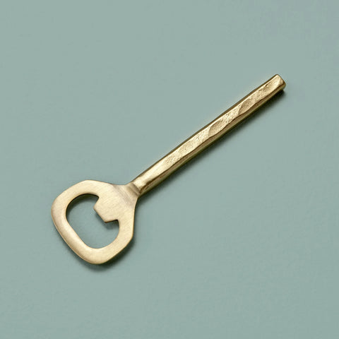 Gold bottle opener on a grey/green background