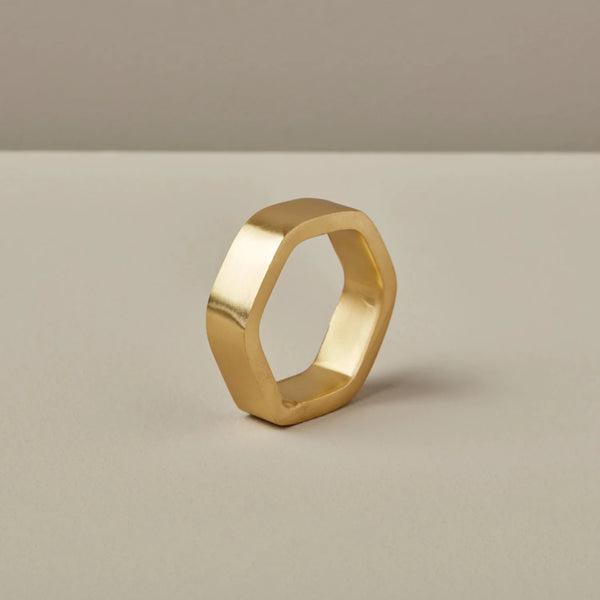 Hexagon brass napkin ring on a beige background