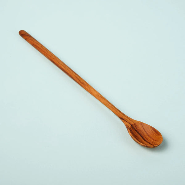 long thin spoon made from teak wood, on a blue background