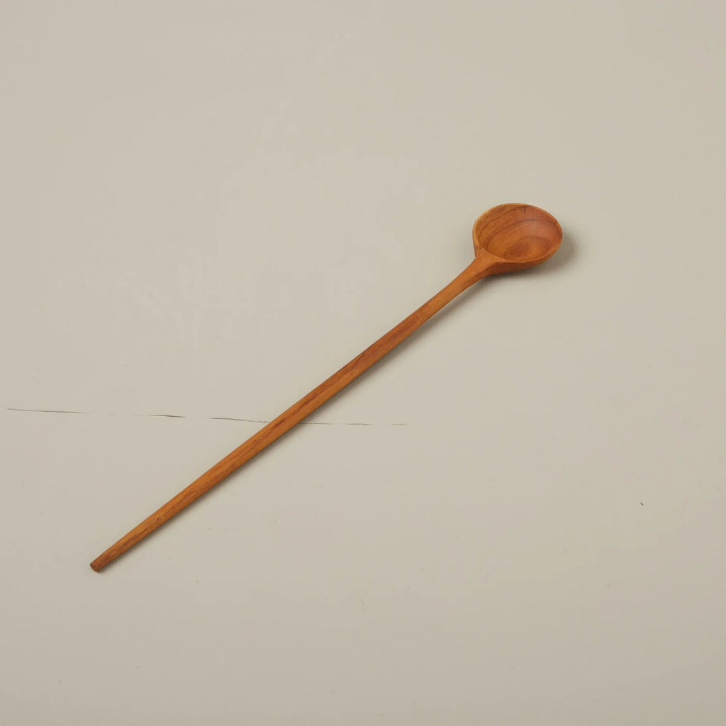 Wooden long spoon laying. Grey background.