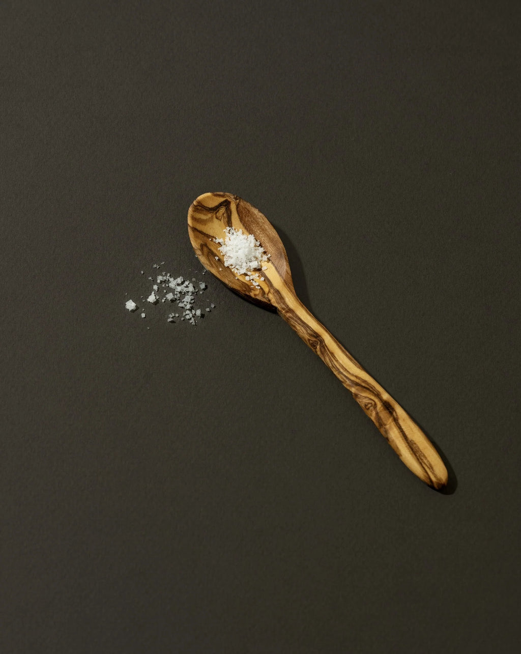 Wooden spoon with salt on a dark background