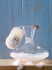 Clear glass carafe with a brush on a wooden surface against a blue wooden background