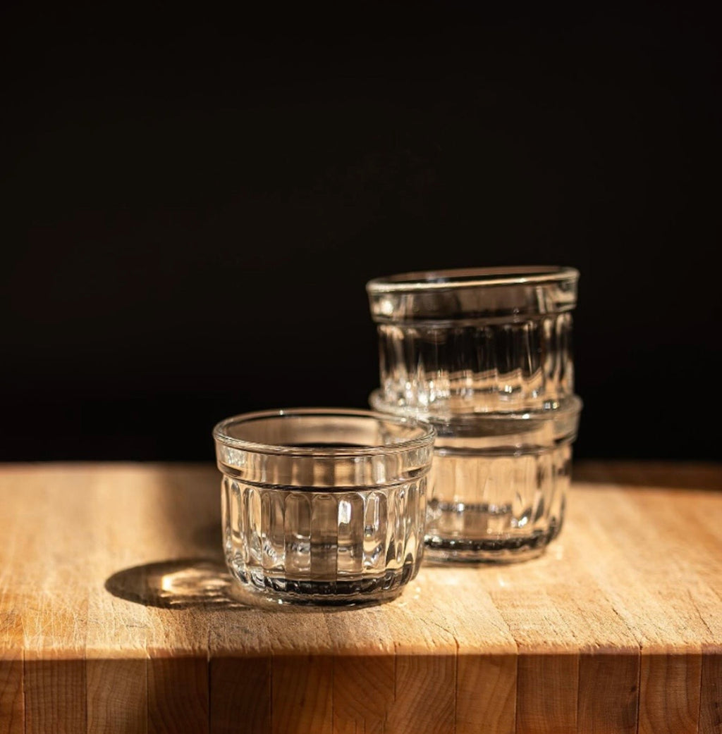 Three clear glass tumblers on a wooden surface with a dark background
