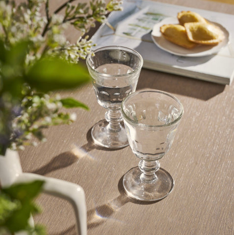 Two clear glasses on a wooden table with a blurred background