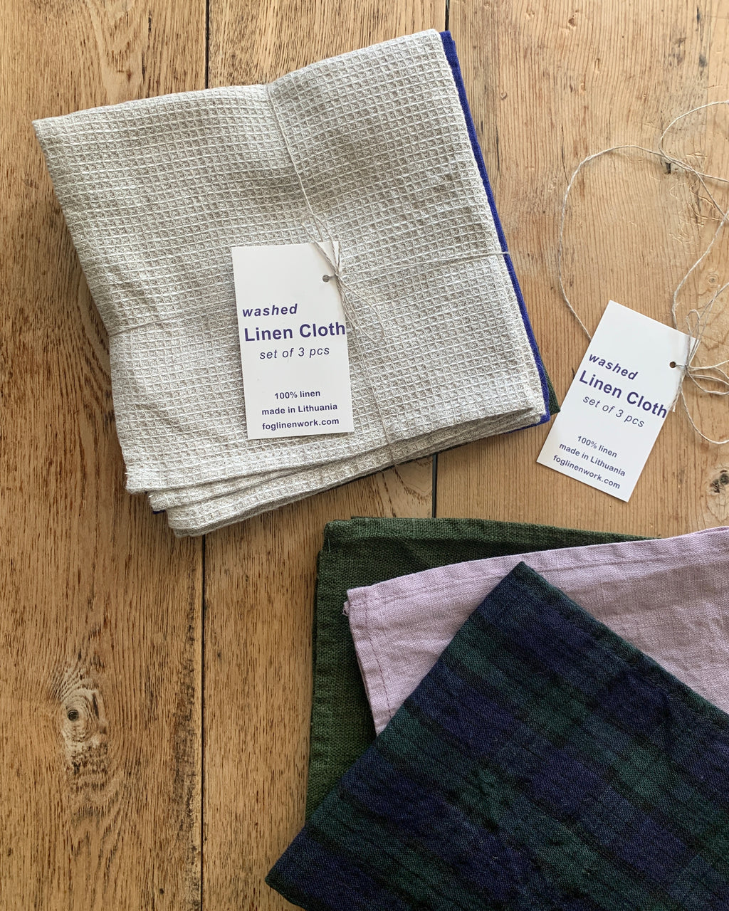 Set of washed linen cloths with tags on a wooden surface