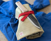 Knife wrapped on a beige tool roll with red strap on blue fabric background