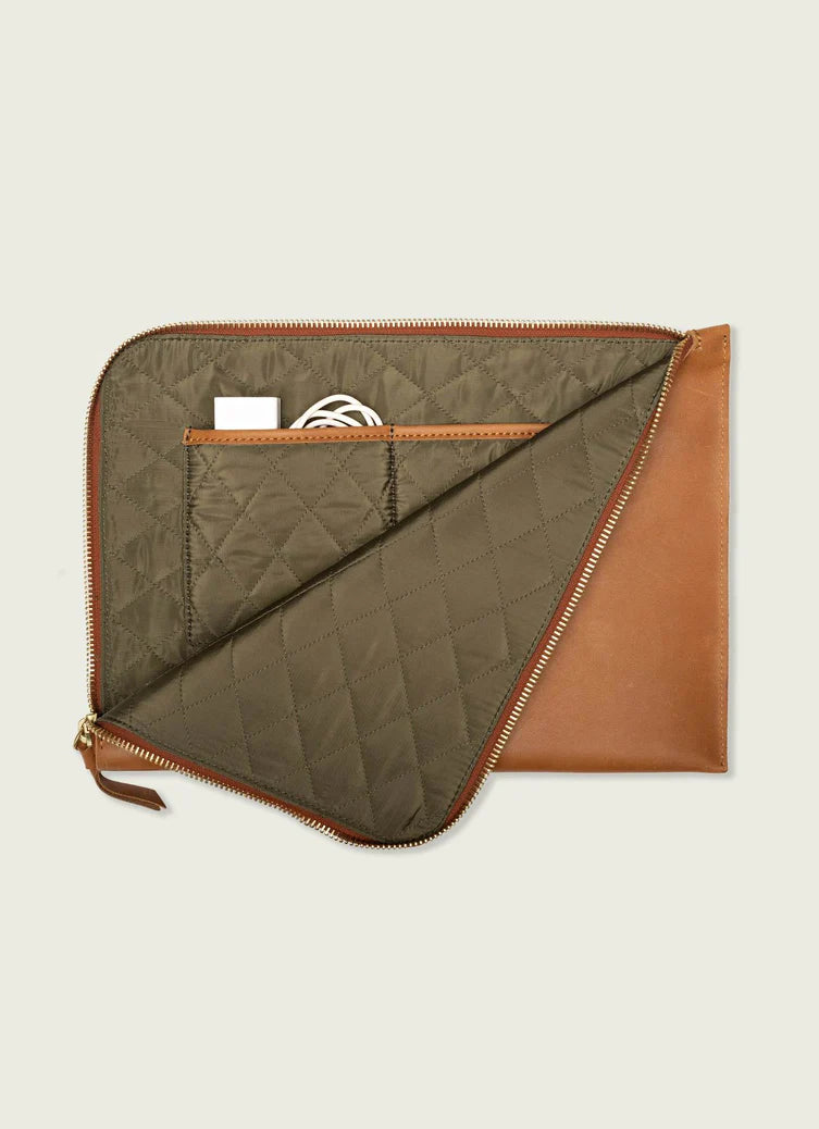 Quilted laptop sleeve with brown leather accents on a beige background