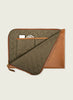 Quilted laptop sleeve with brown leather accents on a beige background