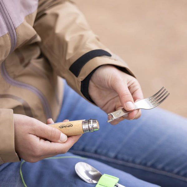 Person holding a fork and knife base with a neutral background