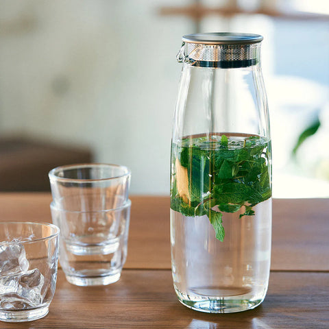 Clear glass carafe with green leaves on a wooden table