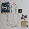 Tote bag with a book, wooden stamps, and a box on a light surface