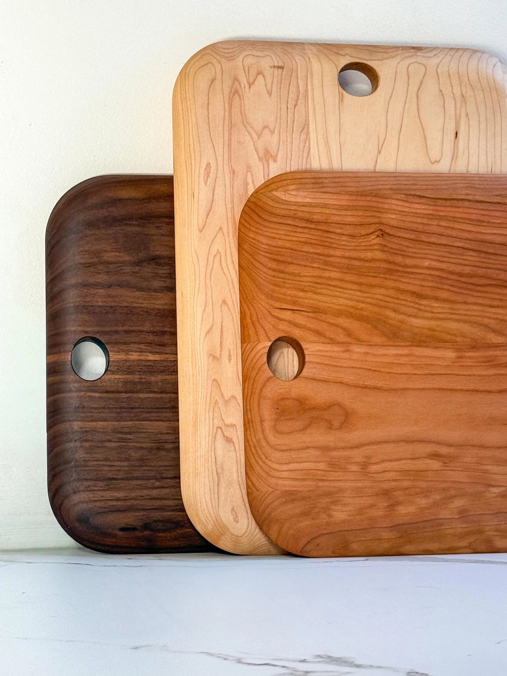 Three wooden cutting boards of different colors on a light background
