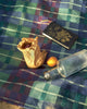 Journal, bottle, and fruit on a checkered picnic blanket