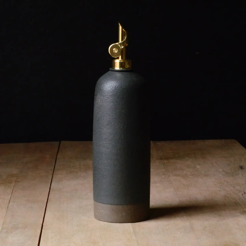 Black ceramic bottle with gold cap on a wooden surface