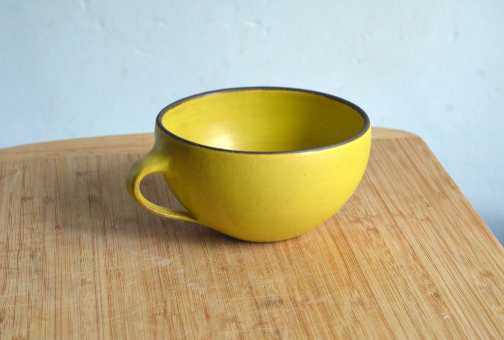 Yellow mug on a wooden surface with a light blue background