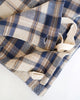 A close-up of a folded plaid kitchen cloth, featuring a navy blue, beige, and brown herringbone pattern with cream canvas straps on a white background.