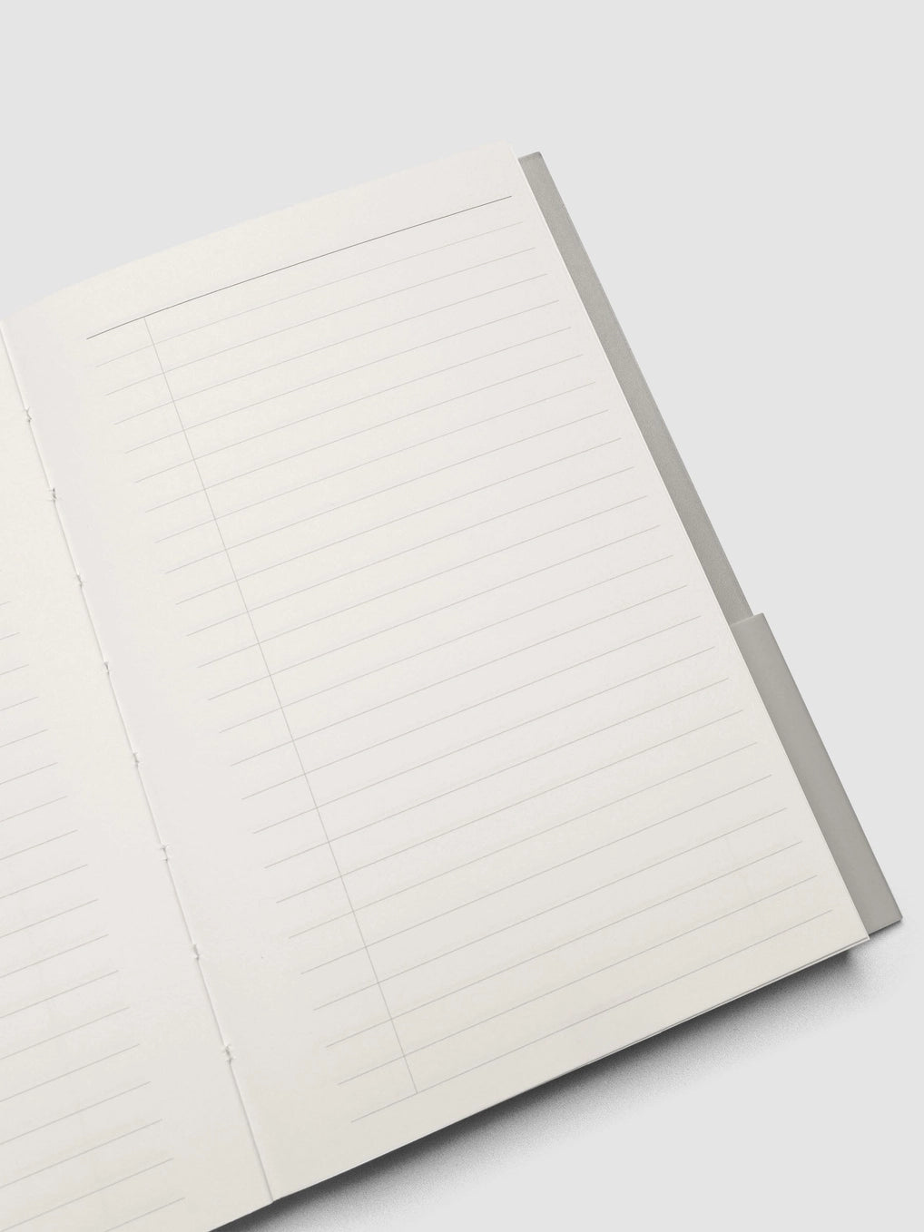 An open lined notebook with white pages and a gray cover, photographed on a light gray background.