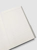 An open lined notebook with white pages and a gray cover, photographed on a light gray background.