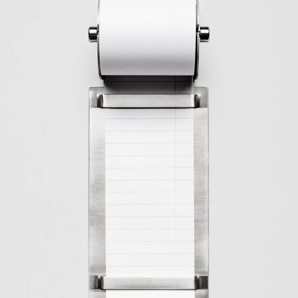 Metallic task roll holder with a roll of white lined paper on a white background