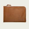 Brown leather laptop sleeve with zipper on a light beige background