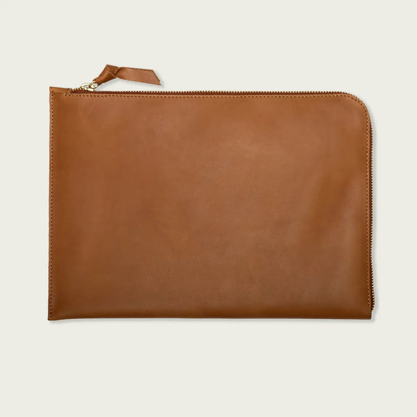 Brown leather laptop sleeve with zipper on a light beige background