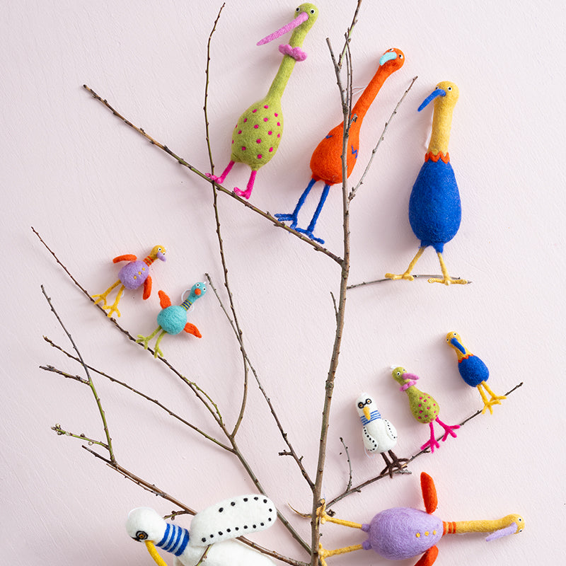 Colorful bird-shaped decorations on a branch against a light background