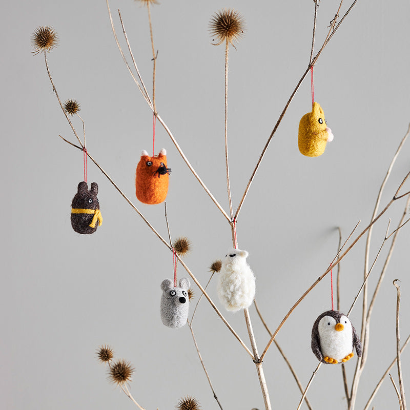 Small animal ornaments hanging from branches against a gray background