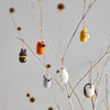 Small animal ornaments hanging from branches against a gray background