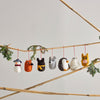 Set of small animal ornaments hanging from a branch against a light background