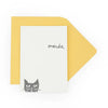 Note card with a cat illustration and 'merde' text on a yellow envelope.