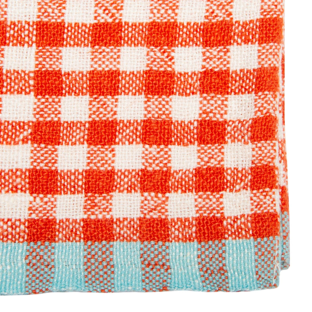A close-up of a woven textile with a red and white gingham check pattern and a light blue border along the bottom edge.