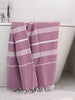 Purple towel with white stripes draped over a bathtub in a bathroom setting