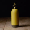 yellow ceramic oil bottle with gold cap on a wooden surface